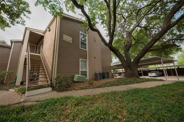 a view of a house with a small yard and a large tree