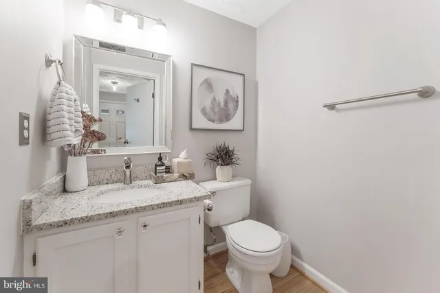 a bathroom with a granite countertop toilet a sink and mirror
