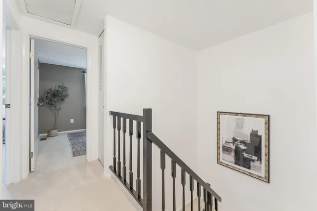a view of a hallway with wooden floor and a bathroom