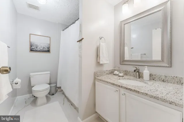 a bathroom with a granite countertop sink and a toilet