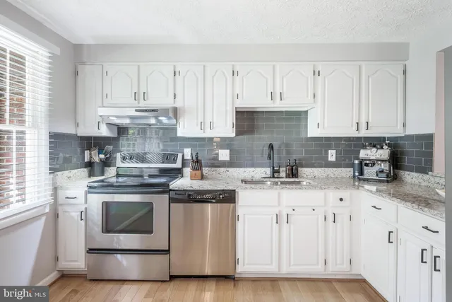 a kitchen with granite countertop white cabinets and white appliances