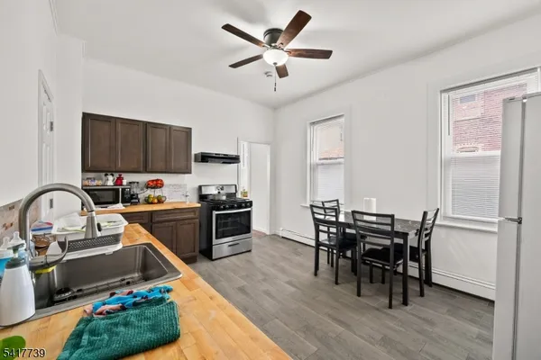 a kitchen with stainless steel appliances granite countertop a stove top oven a sink dishwasher a dining table and chairs with wooden floor