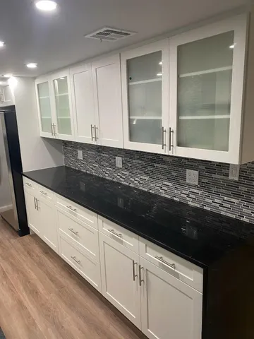 a kitchen with granite countertop white cabinets and sink