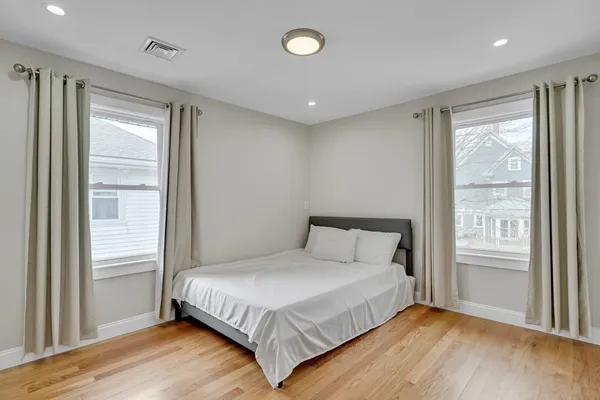 a bedroom with a large bed and wooden floor