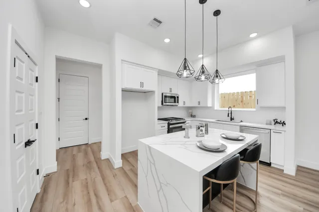 a kitchen with kitchen island a wooden floor and white appliances