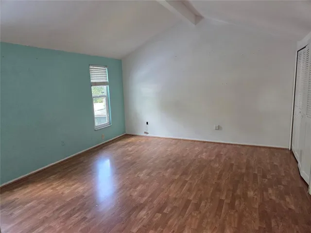 a view of an empty room with wooden floor and closet area