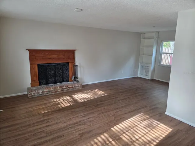 a view of empty room with wooden floor and fireplace