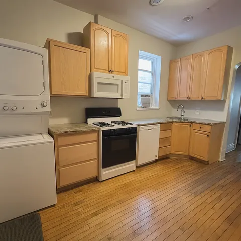 a kitchen with a stove white cabinets wooden floor and a sink