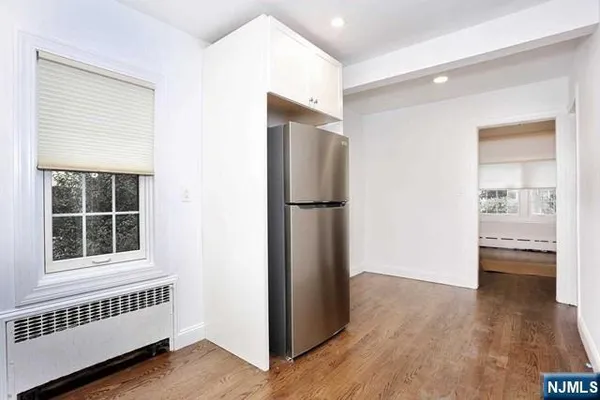 a view of a livingroom with wooden floor and a kitchen space