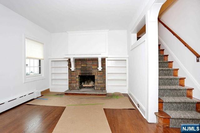 220 Raymond Street Hasbrouck Heights, NJ 07604 - Photo 10 of 36 a view of an empty room with wooden floor fireplace and a window