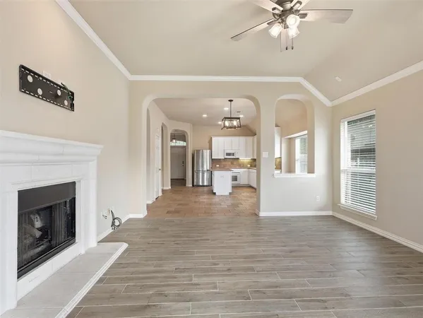a view of a livingroom with wooden floor and a kitchen