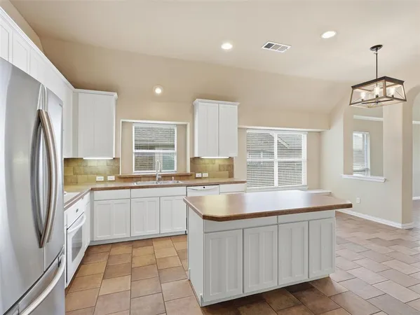 a large kitchen with a large counter top space appliances and cabinets