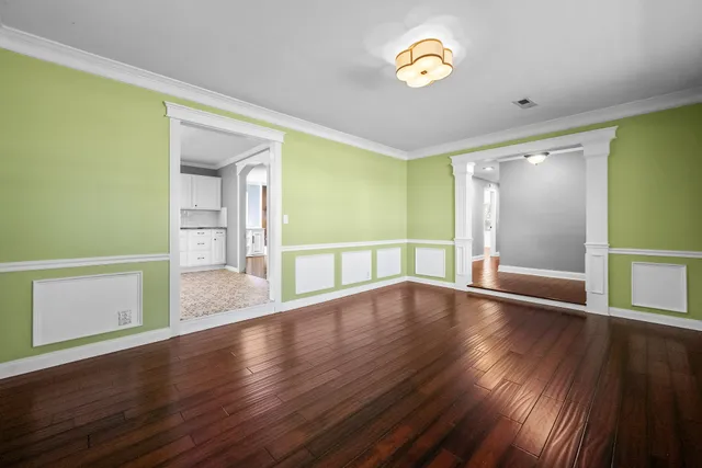 an empty room with wooden floor chandelier fan and windows