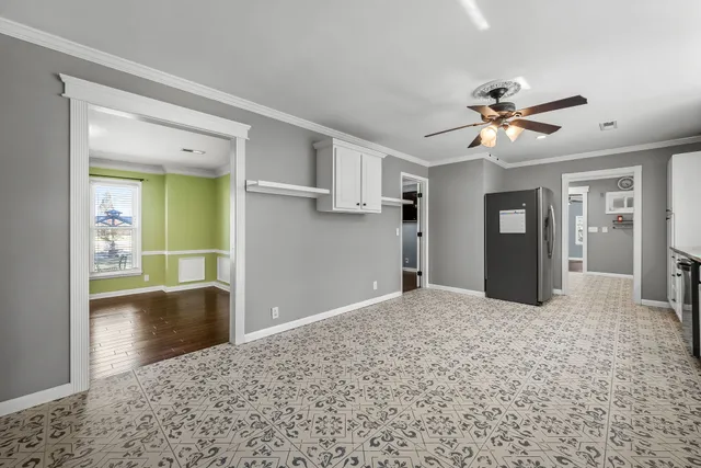 a view of a white house next to a yard with plants and trees