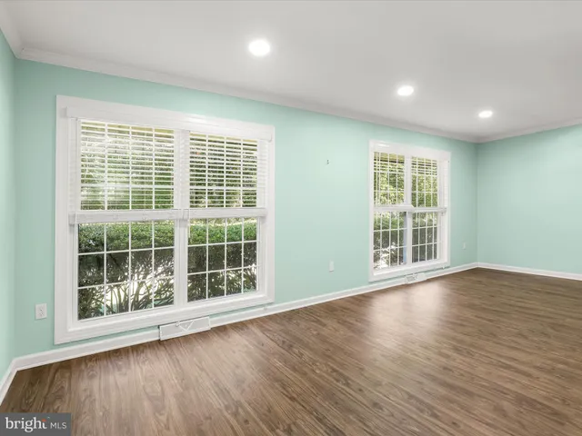a view of an empty room with wooden floor and windows