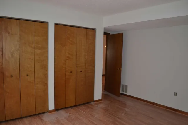 a view of an empty room with wooden floor and closet area