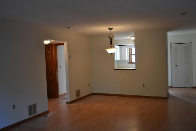 an empty room with window and wooden floor