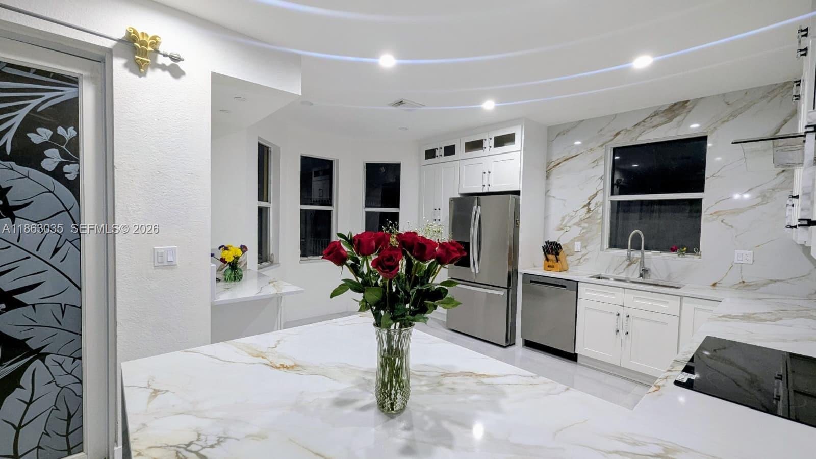 a white kitchen with a sink potted plant and a large window