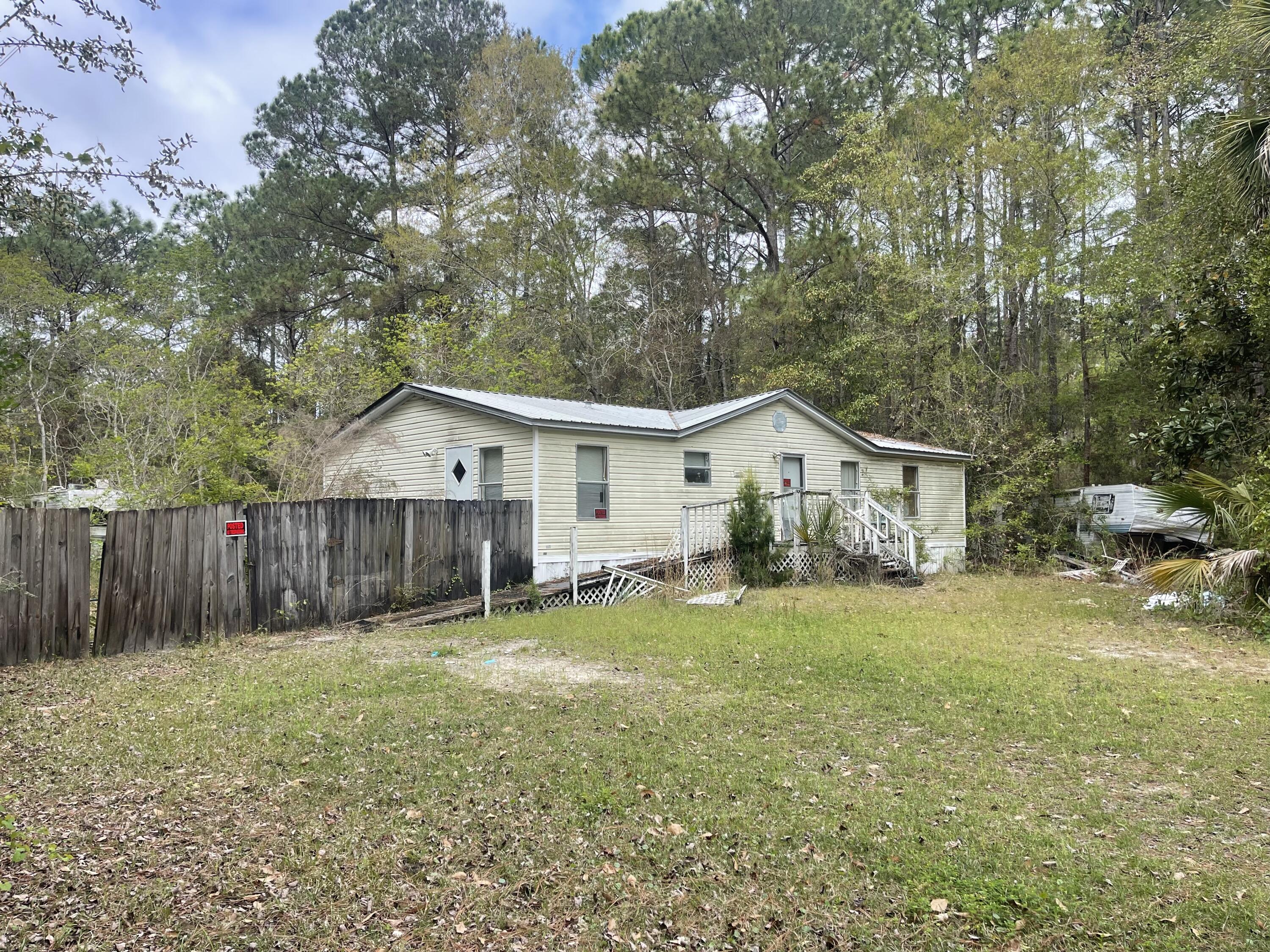 a front view of house with wooden fence and trees