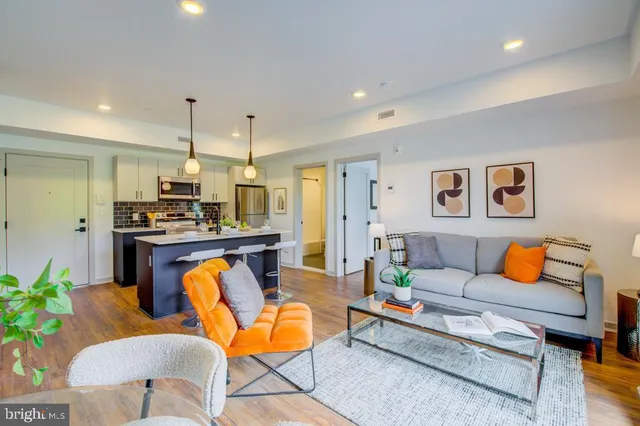 a living room with furniture kitchen view and a chandelier