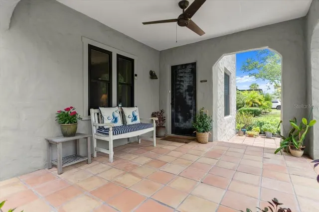a view of a patio with a table and chairs potted plants and floor to ceiling window