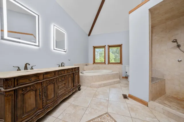 a spacious bathroom with a tub sink and mirror