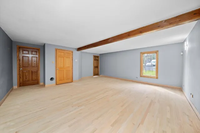a view of an empty room with window and wooden floor