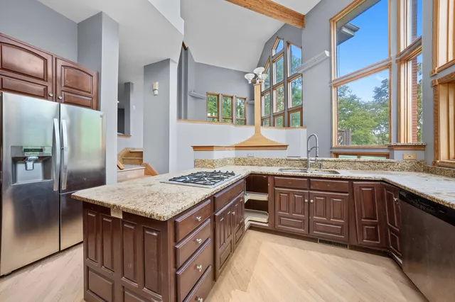 a kitchen with stainless steel appliances granite countertop a stove a sink and a refrigerator