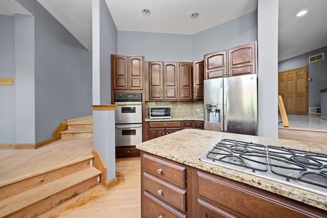 a living room with stainless steel appliances kitchen island granite countertop furniture and a refrigerator
