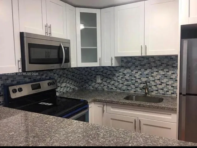 a kitchen with granite countertop a stove and a microwave