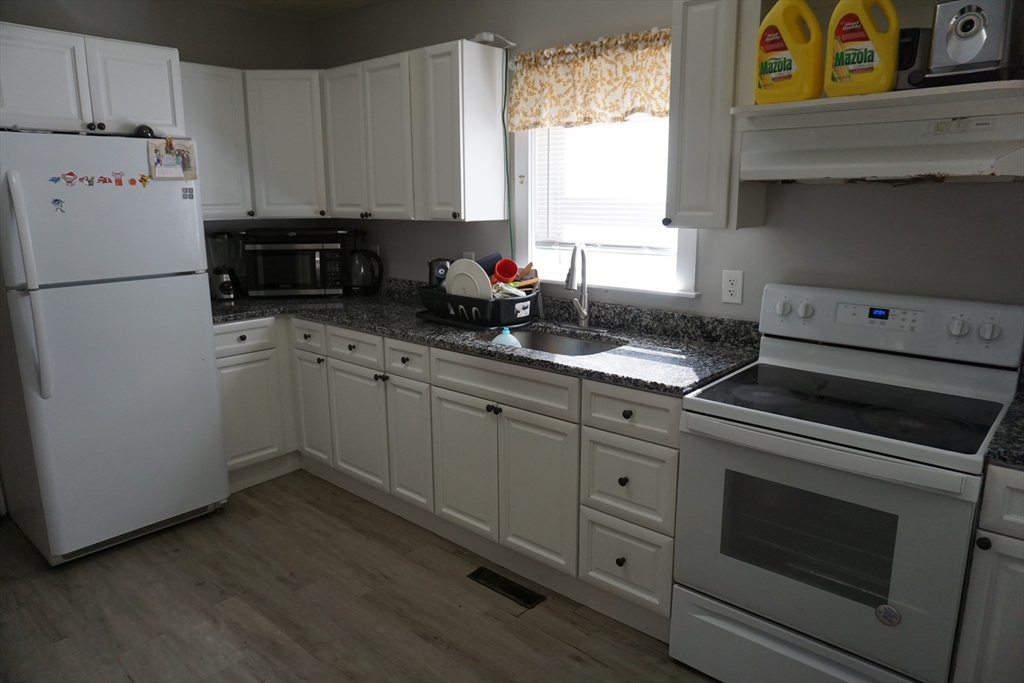 5-7 Summer Street Maynard, MA 01754 - Photo 19 of 28 a kitchen with granite countertop white cabinets and white appliances