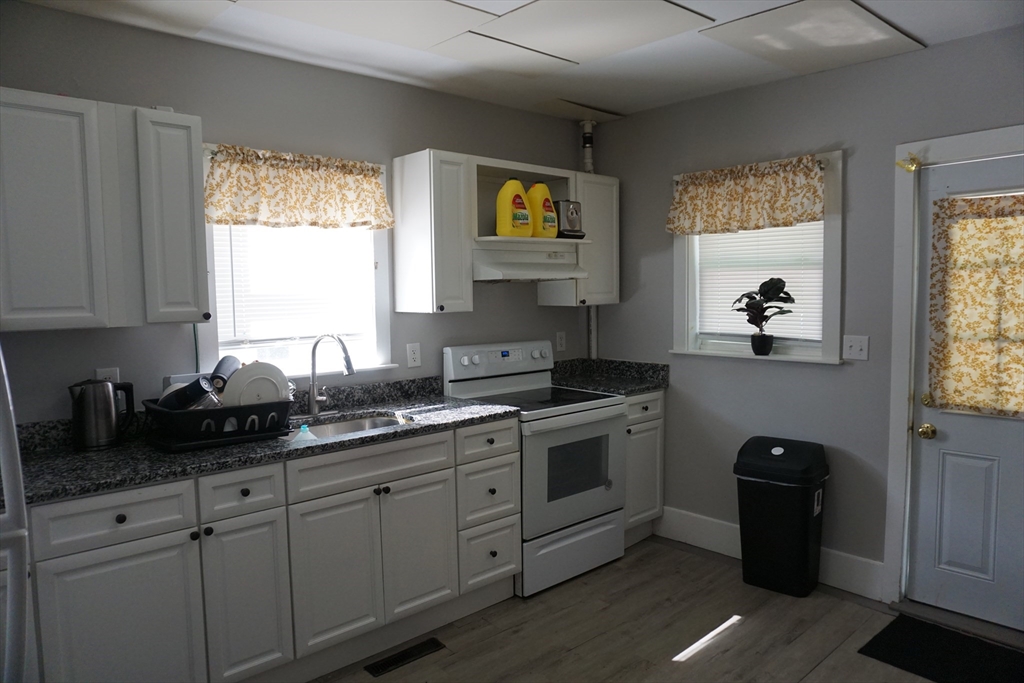 5-7 Summer Street Maynard, MA 01754 - Photo 22 of 28 a kitchen with stainless steel appliances granite countertop white cabinets and a window