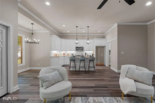 a living room with furniture kitchen view and a wooden floor