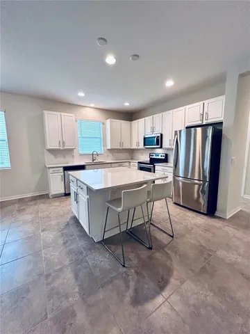 a kitchen with kitchen island granite countertop a sink a counter top space stainless steel appliances and cabinets