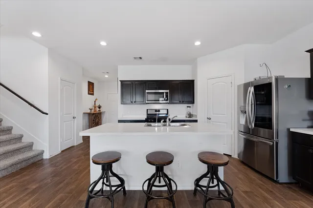 a kitchen with stainless steel appliances a dining table chairs refrigerator and microwave