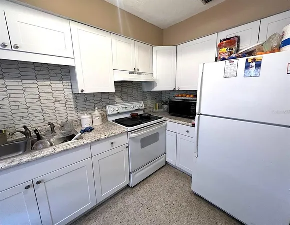a white kitchen with sink a refrigerator and cabinets