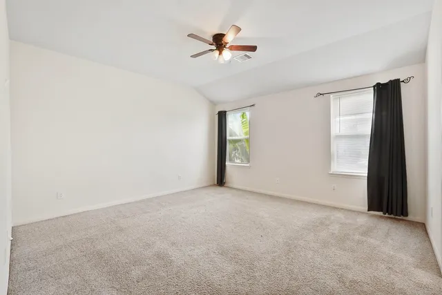 an empty room with fan and windows