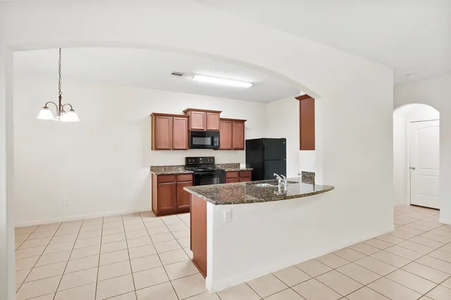 a kitchen with kitchen island granite countertop a sink a stove a microwave a counter top space and cabinets