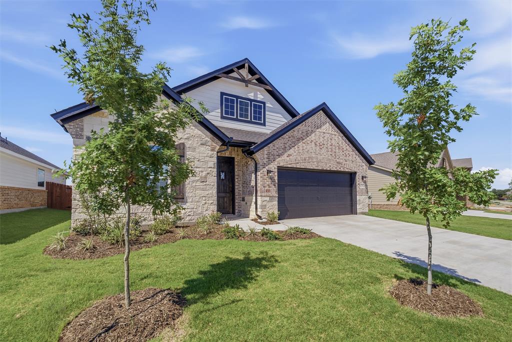 1213 Colca Drive Springtown, TX 76082 - Photo 3 of 23 Stone and brick exterior with dark trim accents, featuring a two-car garage, established front landscaping, and a concrete driveway