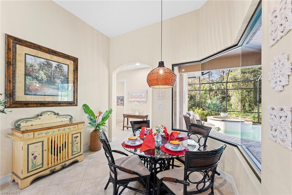 8838 Lely Island Circle Naples, FL 34113 - Photo 17 of 47 a dining room with furniture a chandelier and wooden floor