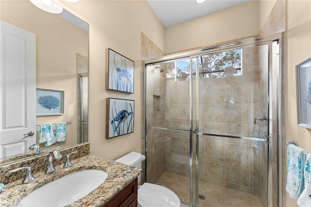 8838 Lely Island Circle Naples, FL 34113 - Photo 24 of 47 a bathroom with a granite countertop tub shower sink and mirror