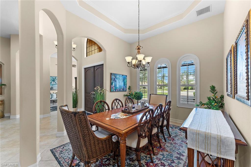 8838 Lely Island Circle Naples, FL 34113 - Photo 9 of 47 a dining room with furniture a chandelier and a rug