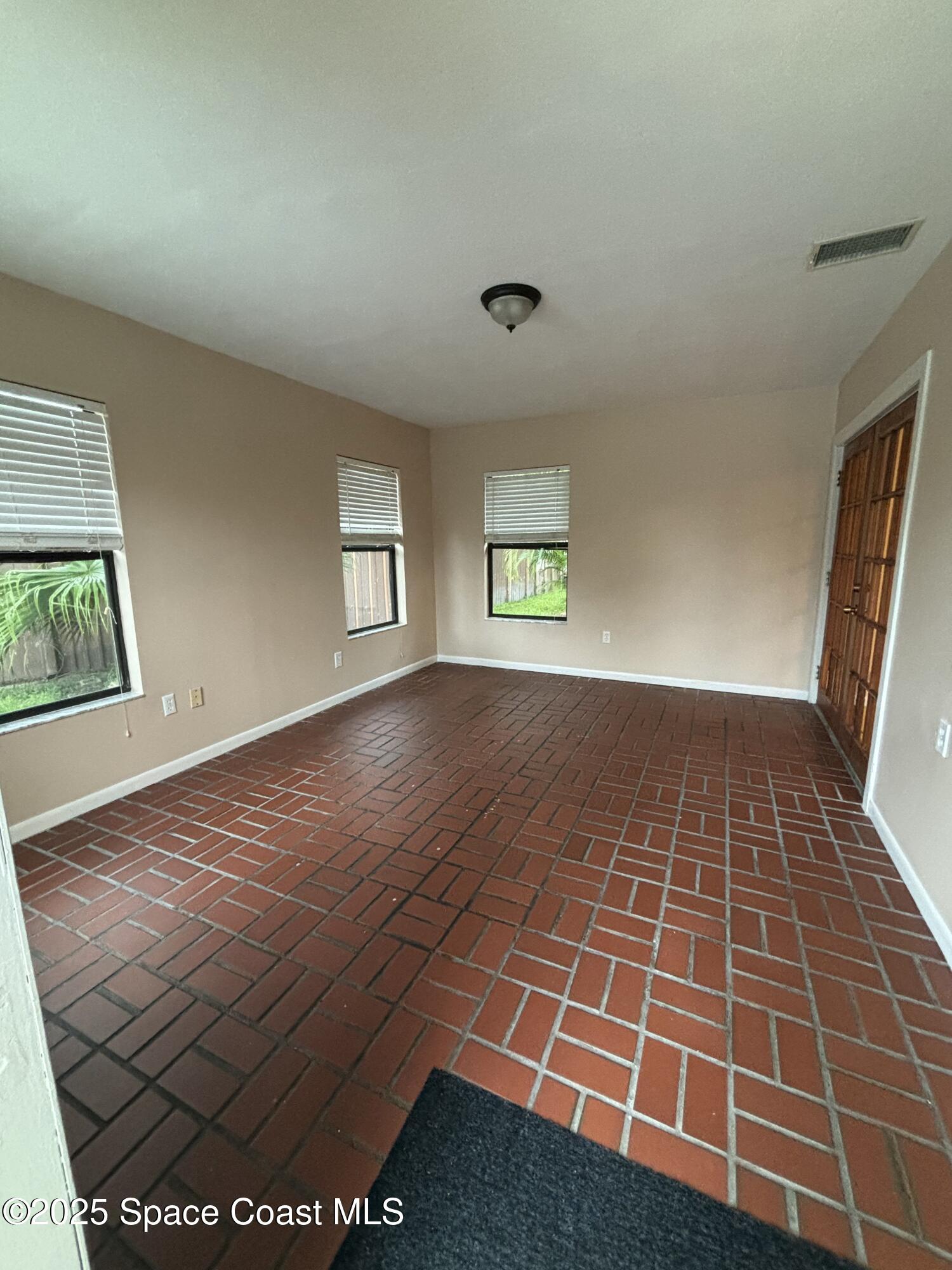 1201 Northeast Tropicana Road Palm Bay, FL 32905 - Photo 9 of 23 an empty room with wooden floor and windows