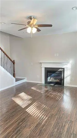 a view of an empty room with wooden floor fireplace and a window