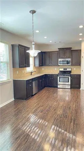a large kitchen with stainless steel appliances granite countertop a large counter top and wooden floors