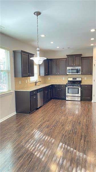 4408 Black Hills Drive Northwest Kennesaw, GA 30144 - Photo 9 of 33 a large kitchen with stainless steel appliances granite countertop a large counter top and wooden floors