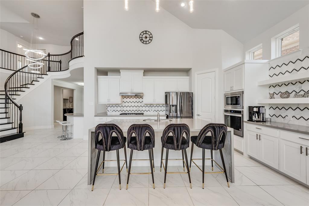 2341 Haft River Road Frisco, TX 75034 - Photo 10 of 36 Kitchen featuring backsplash, high vaulted ceiling, a breakfast bar area, white cabinets, and a kitchen island with sink