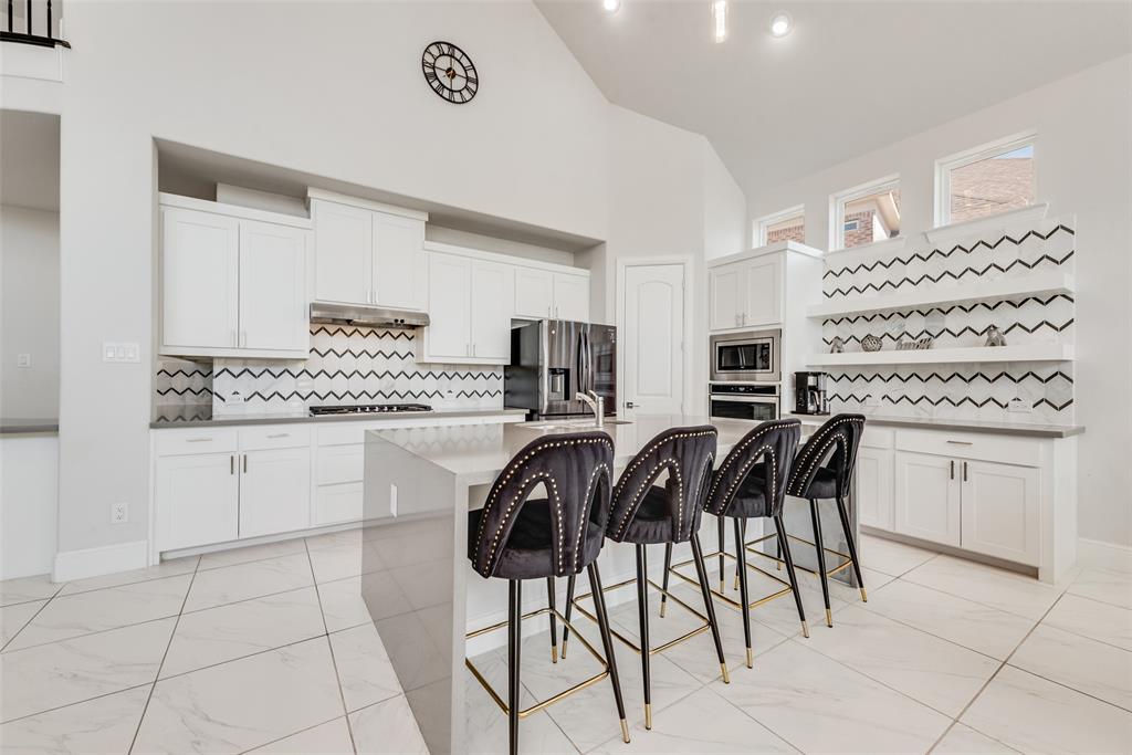 2341 Haft River Road Frisco, TX 75034 - Photo 11 of 36 Kitchen featuring tasteful backsplash, high vaulted ceiling, white cabinets, a kitchen breakfast bar, and an island with sink