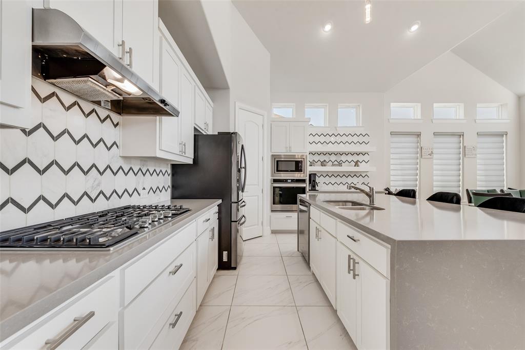 2341 Haft River Road Frisco, TX 75034 - Photo 8 of 36 Kitchen with white cabinetry, backsplash, under cabinet range hood, light stone counters, and appliances with stainless steel finishes