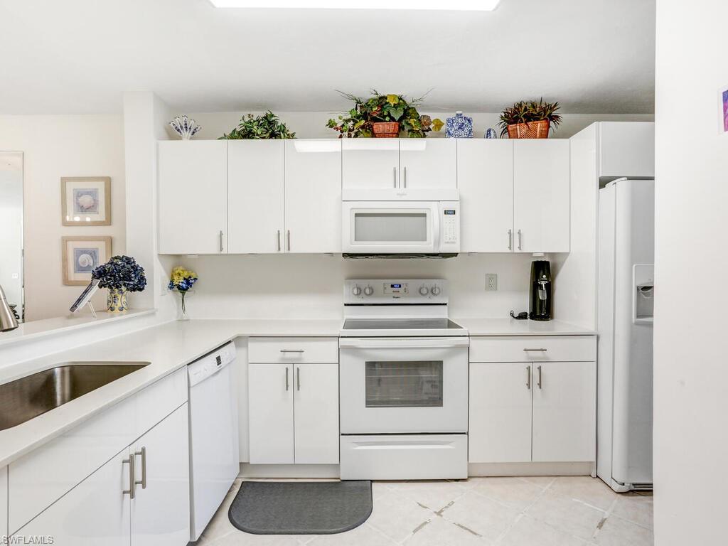 1232 Commonwealth Circle, Unit P102 Naples, FL 34116 - Photo 13 of 30 a kitchen with white cabinets and sink